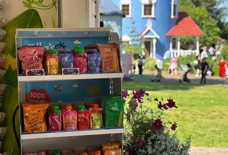Ella's Kitchenin promopiste Muumimaailmassa. Taustalla Muumitalo ja hyllyssä Ella'sin tuotteita.